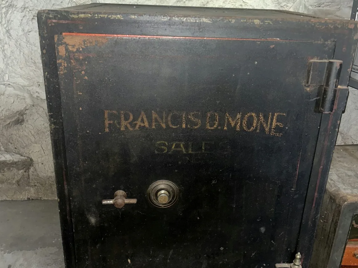 Antique Francis D. Mone commercial fireproof safe standing in a stone-foundation basement — a high-mass safe of the class surveyed in place and planned under SIR before it moves
